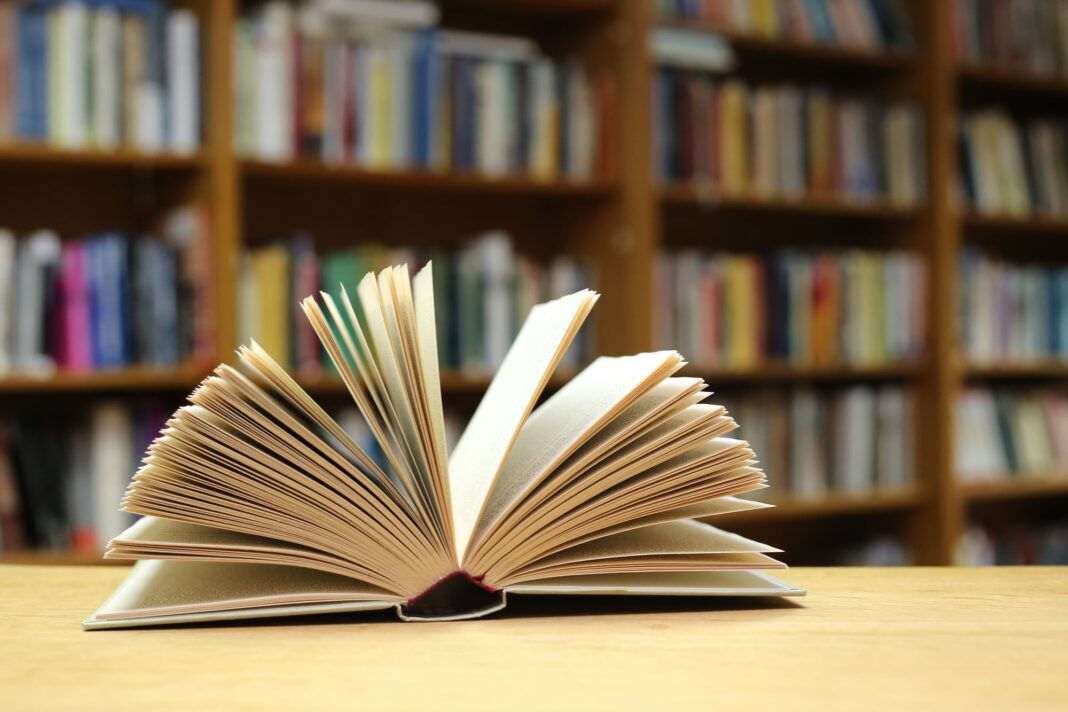 Persona escribiendo una carta en una mesa de café, con un buzón rojo antiguo de fondo