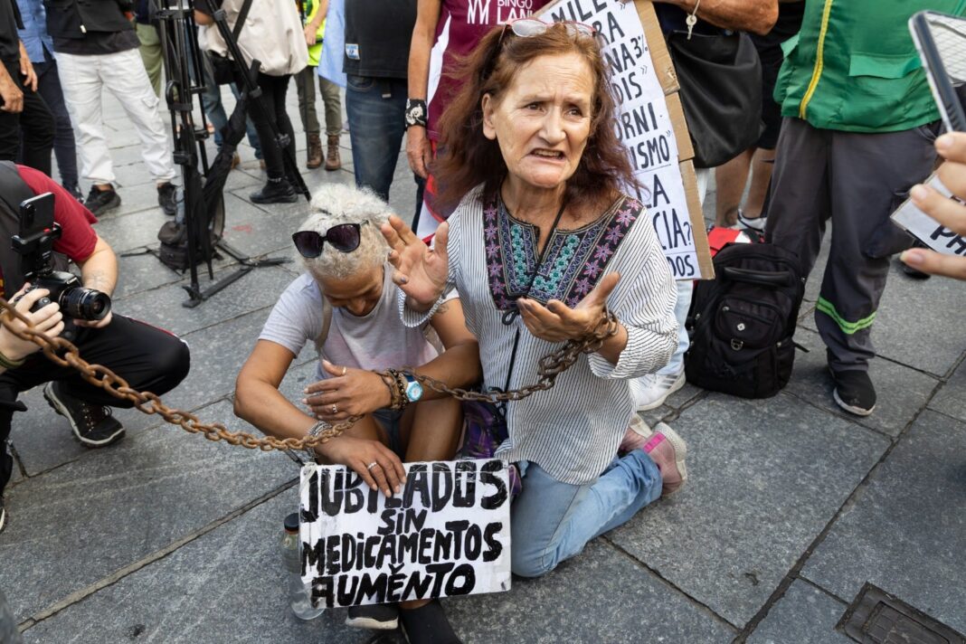 Dos mujeres jubiladas realizan una protesta encadenada en la vía pública.