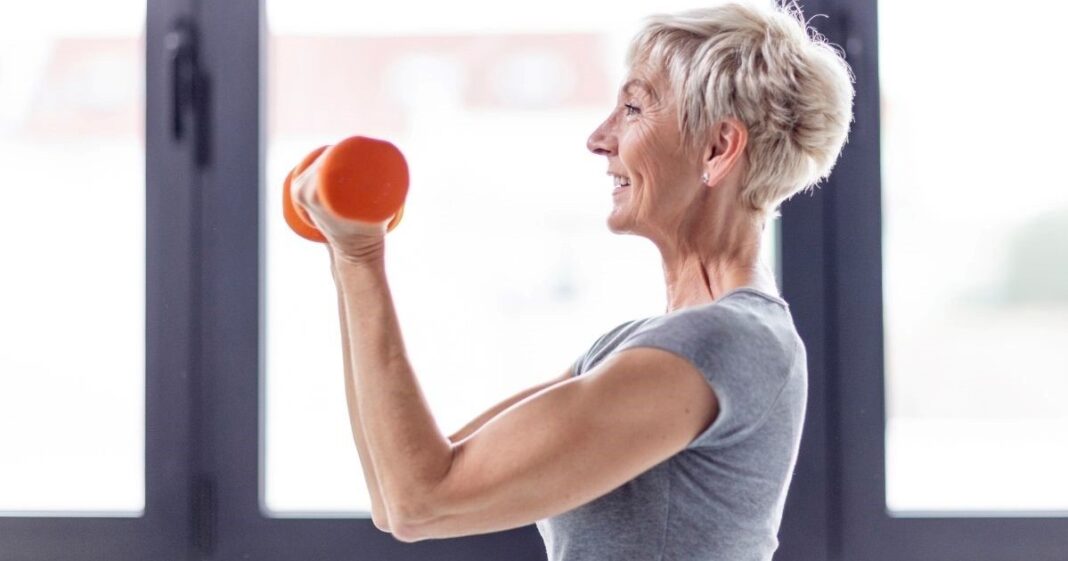 Persona mayor realizando ejercicios suaves de fuerza para los brazos en su hogar.