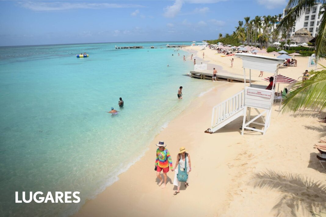 Playa de arena blanca y aguas turquesas en Jamaica, con palmeras.