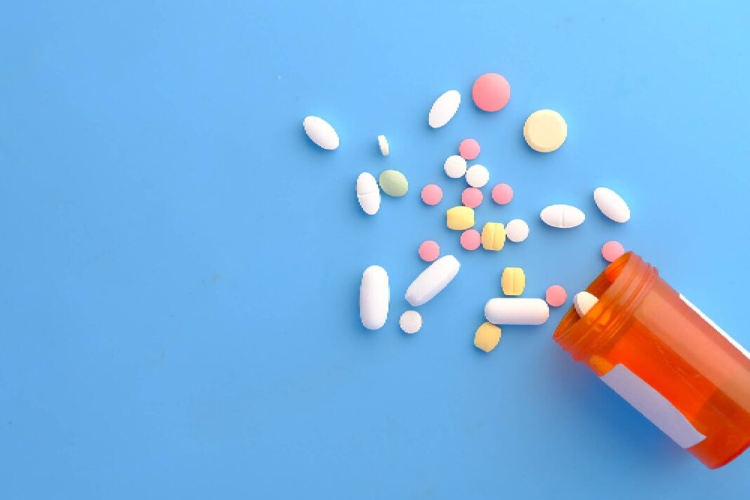 Botiquín con medicamentos varios y una persona mayor tomando una pastilla