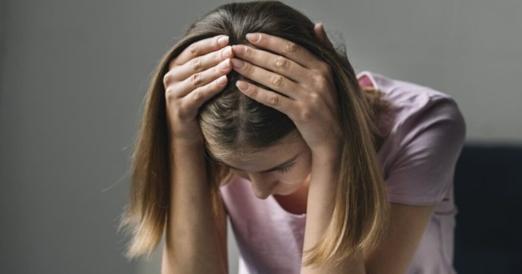 Persona mirando por una ventana con expresión pensativa, representando la incertidumbre y la ansiedad.