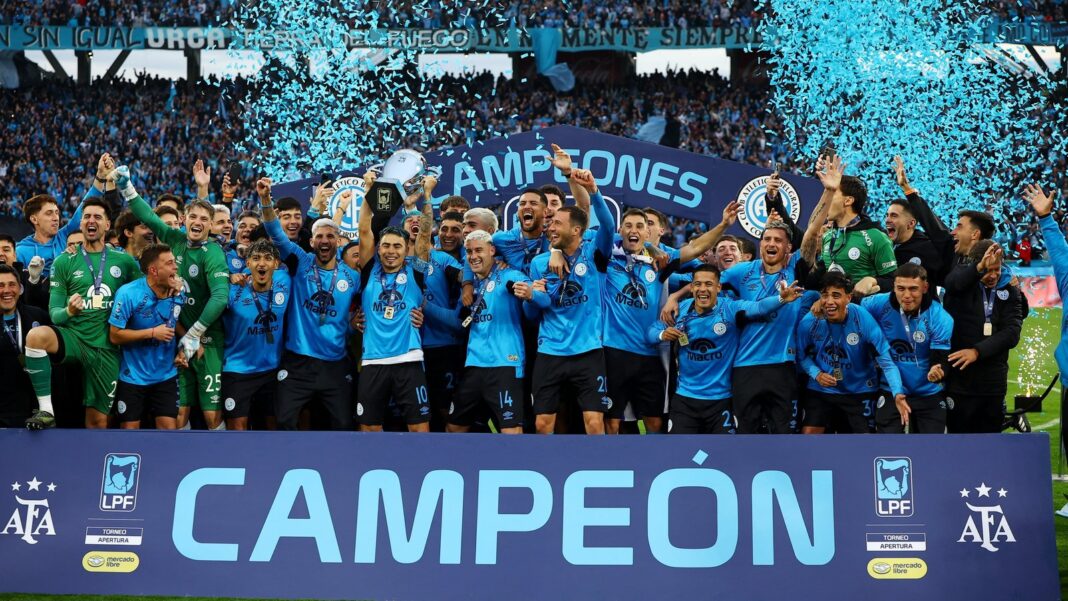 Jugadores de Belgrano celebran con el trofeo del Torneo Apertura 2026 en el campo del estadio Mario Alberto Kempes