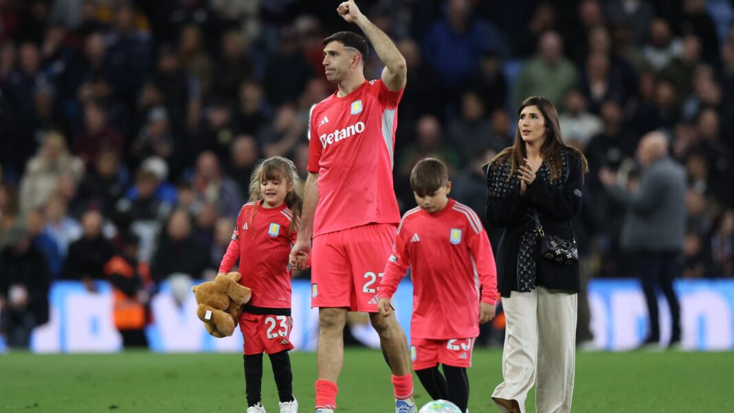 Emiliano Dibu Martínez abraza a su hijo Santino en el césped de Villa Park durante los festejos por la clasificación a la Champions League