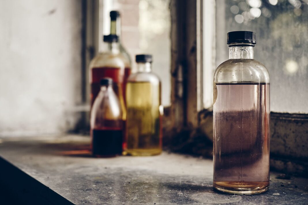 Botella de licor artesanal y advertencia de peligro