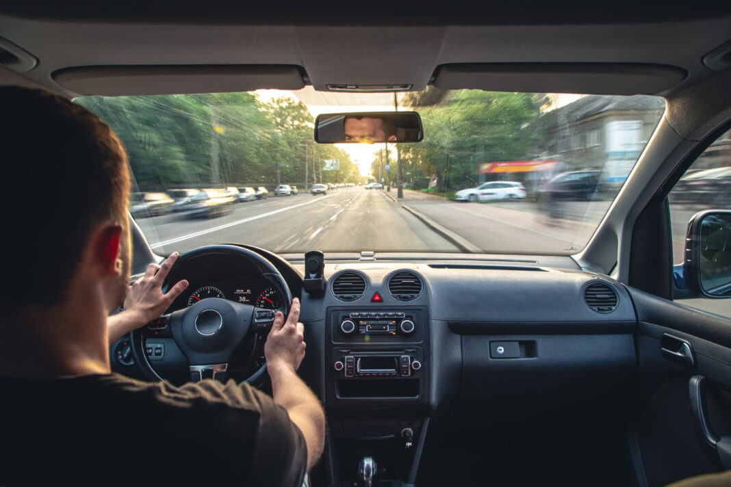 Tablero analógico de un auto clásico con velocímetro y tacómetro físicos, volante de cuero y radio antigua