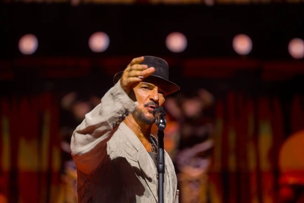Ricardo Arjona en concierto en Paraguay con traje oscuro y sombrero