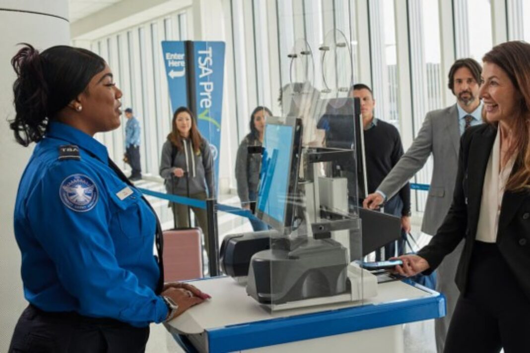 Pasajero en aeropuerto con cartel de TSA PreCheck