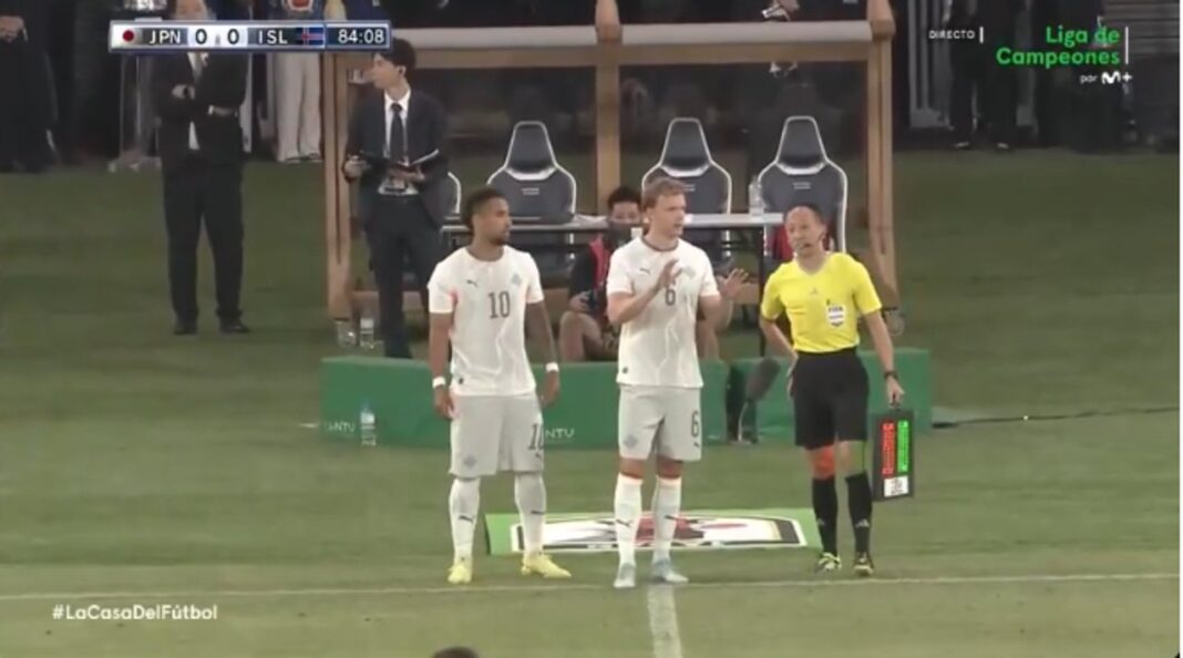 Árbitro mostrando tarjeta amarilla por demora en cambio durante partido de fútbol