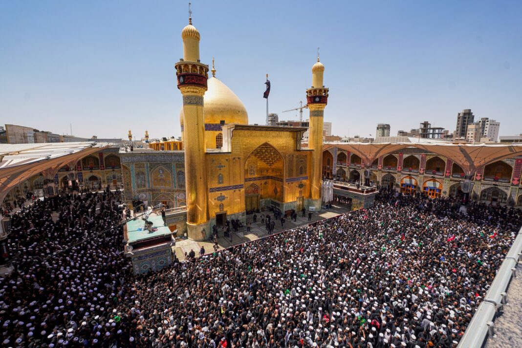 Multitud portando banderas iraníes y retratos de Khamenei en una procesión fúnebre en Nayaf, Irak