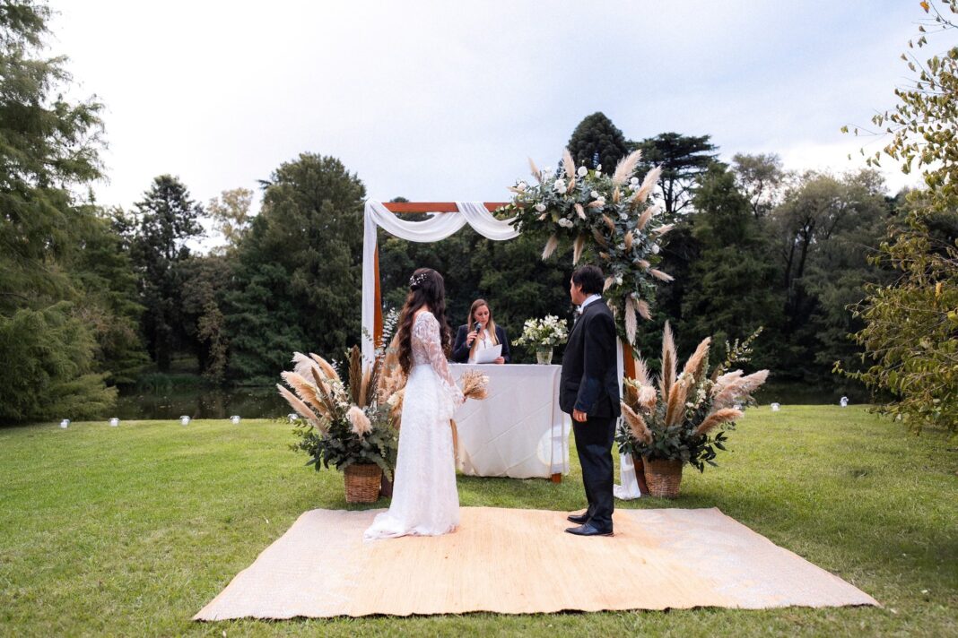Pareja de novios en una ceremonia al aire libre con invitados formando una media luna