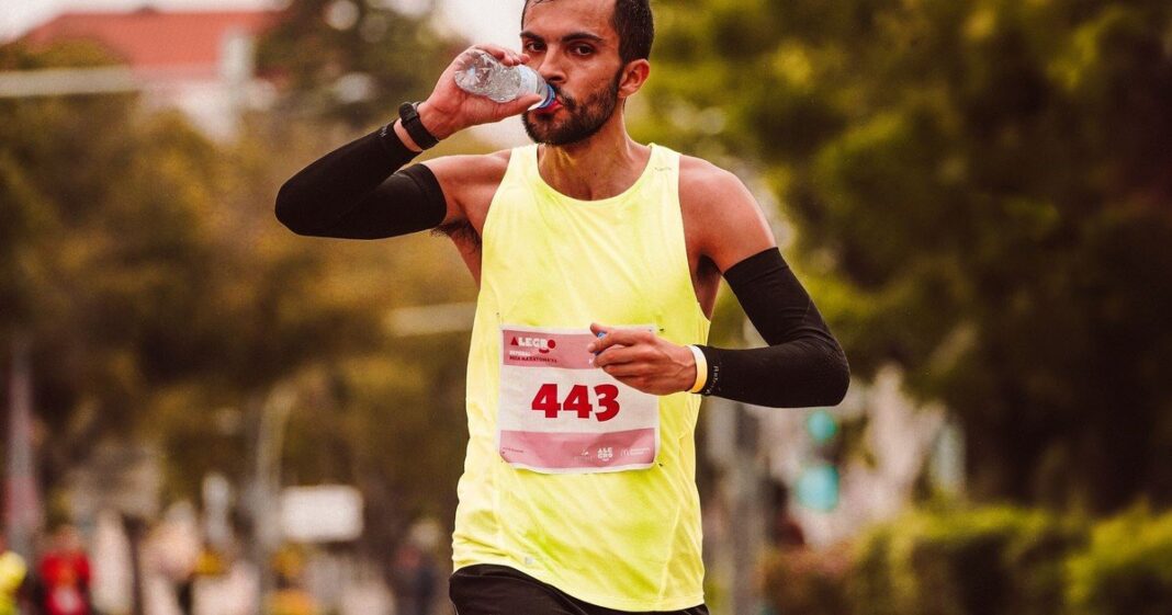 Persona hidratándose durante una carrera al aire libre