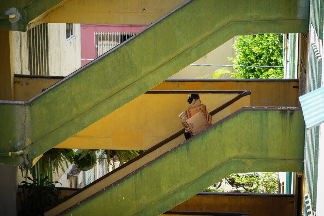 Mujer cargando cartones frente a un edificio en revisión estructural en Cali, Colombia