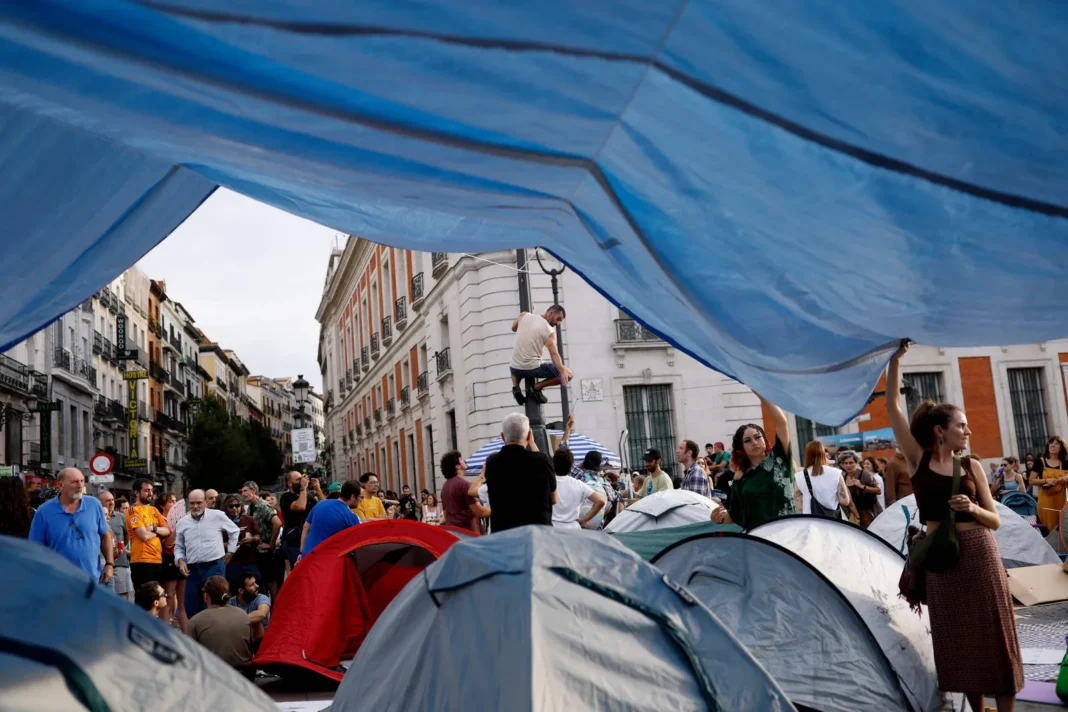 Jóvenes bañándose en la fuente de la Puerta del Sol durante la acampada por la crisis de vivienda en Madrid